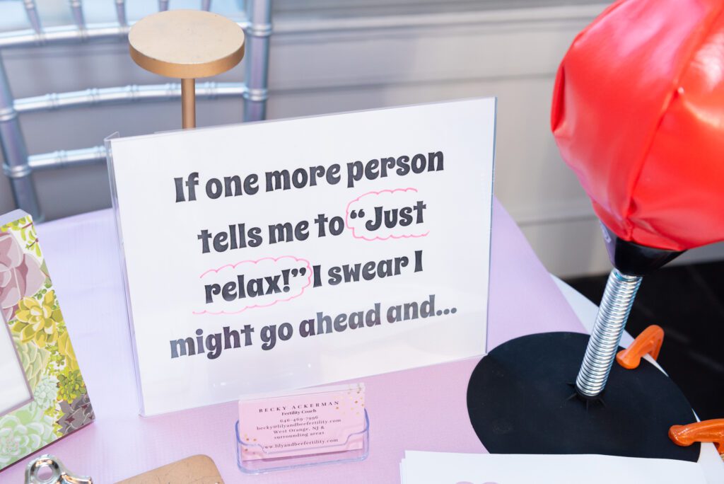 A sign with "If one more person tells me to "Just relax" I swear I might go ahead and ..." at a vendor's table.