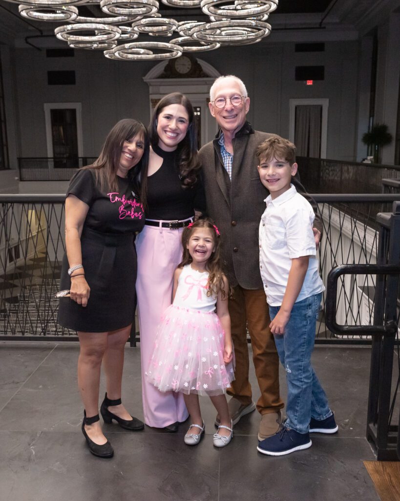 The female owner and host of the embroidery workshop posing and smiling for a picture with her parents and two children at her event.