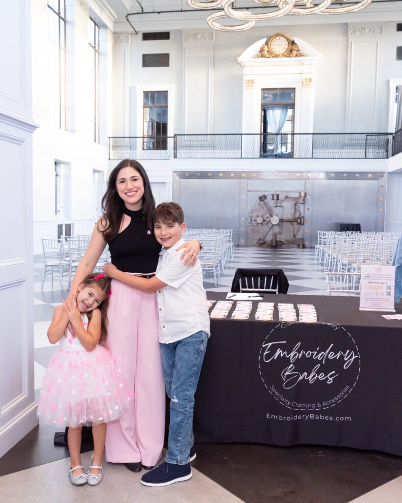 The female owner and host of the embroidery workshop posing and smiling for a picture with her two children at her event.