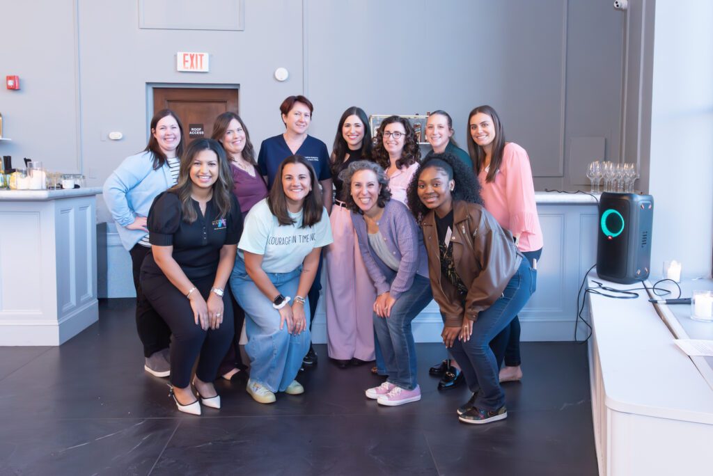 A group photo of 11 women and sponsors at an embroidery workshop event.