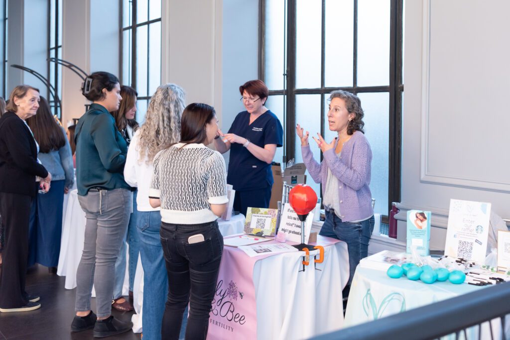 A group of women business owners & event sponsors are talking to the women attendees at an event.