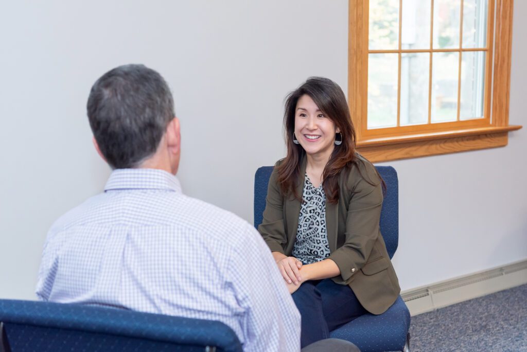 A female Asian executive coach & advisor smiling during an in person client meeting in her office.