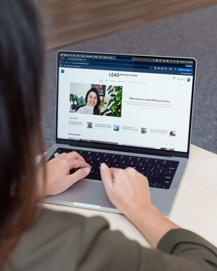 A female Asian executive coach & advisor working on her laptop in her office.