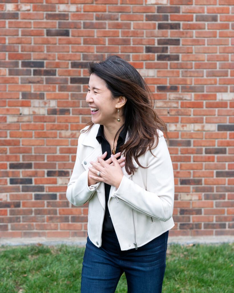 A female Asian executive coach & advisor laughing for her outdoor personal branding session.