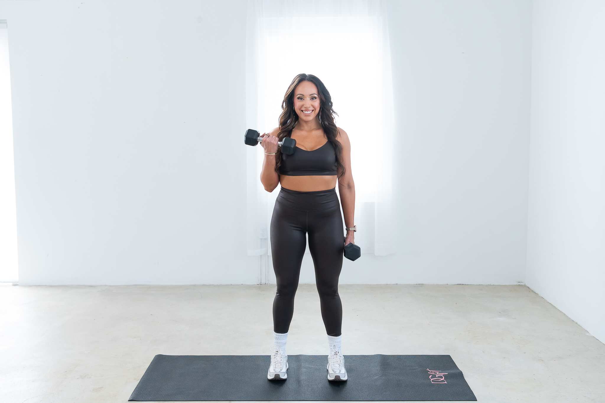A female fitness trainer posing with weights for her branding photoshoot.