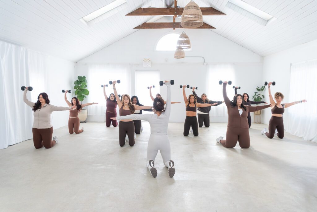 A female fitness trainer teaching a group class with weights.