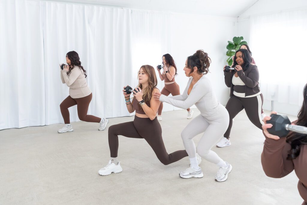 A female fitness trainer assisting her student during a weight lift exercise.