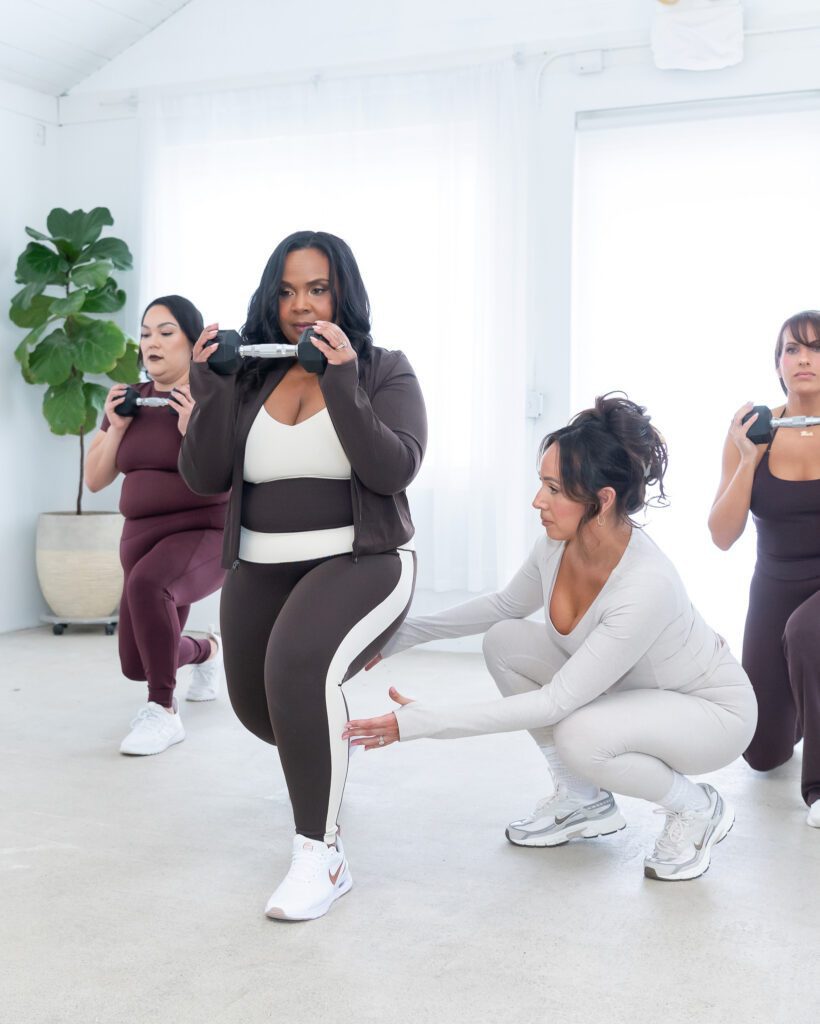 A female fitness trainer assisting her student during a weight lift exercise.