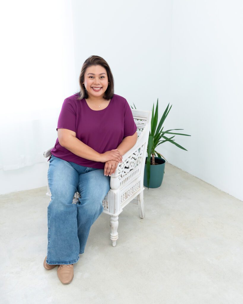 A female photo magnets creator in a purple blouse sitting and posing for her branding photo session.