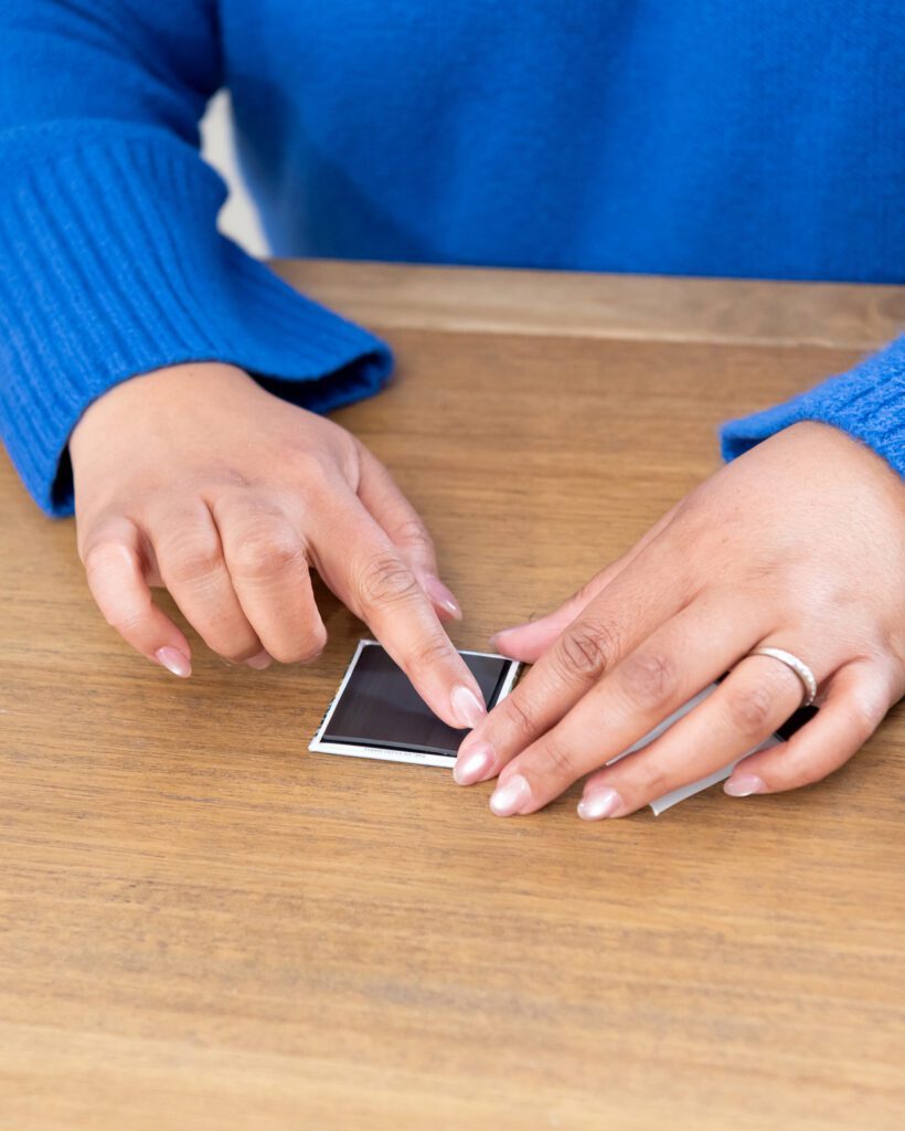 A female photo magnets creator gluing the magnet on the back of the photo print out.